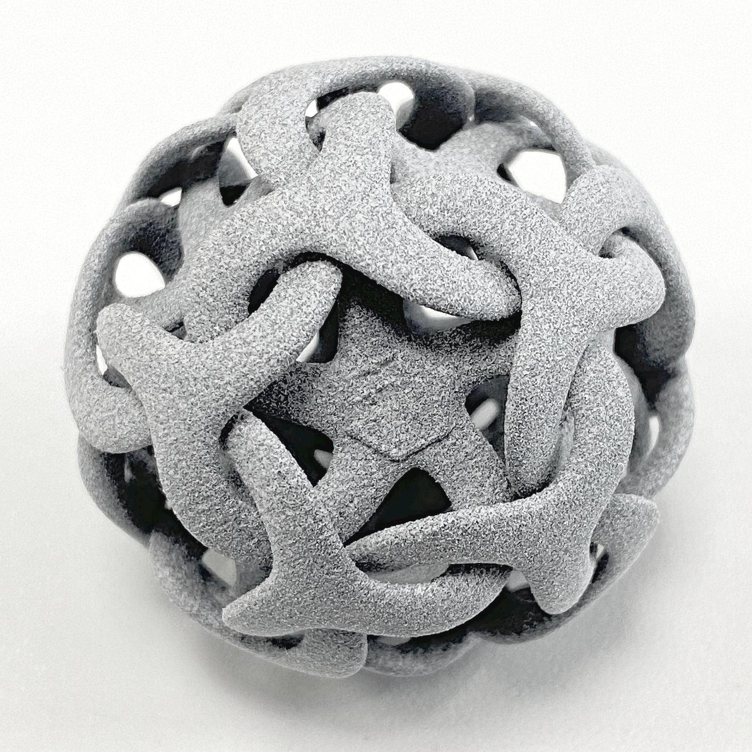 Hellgrauer, golfballgroßer Ball aus dem 3D-Drucker mit Gewebestruktur
